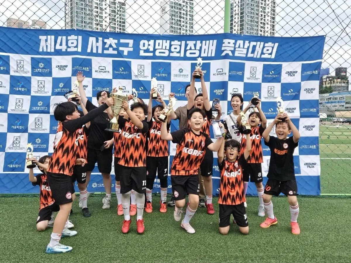 풋살대회에서 트로피를 들고 환호하는 아이들과 선생님