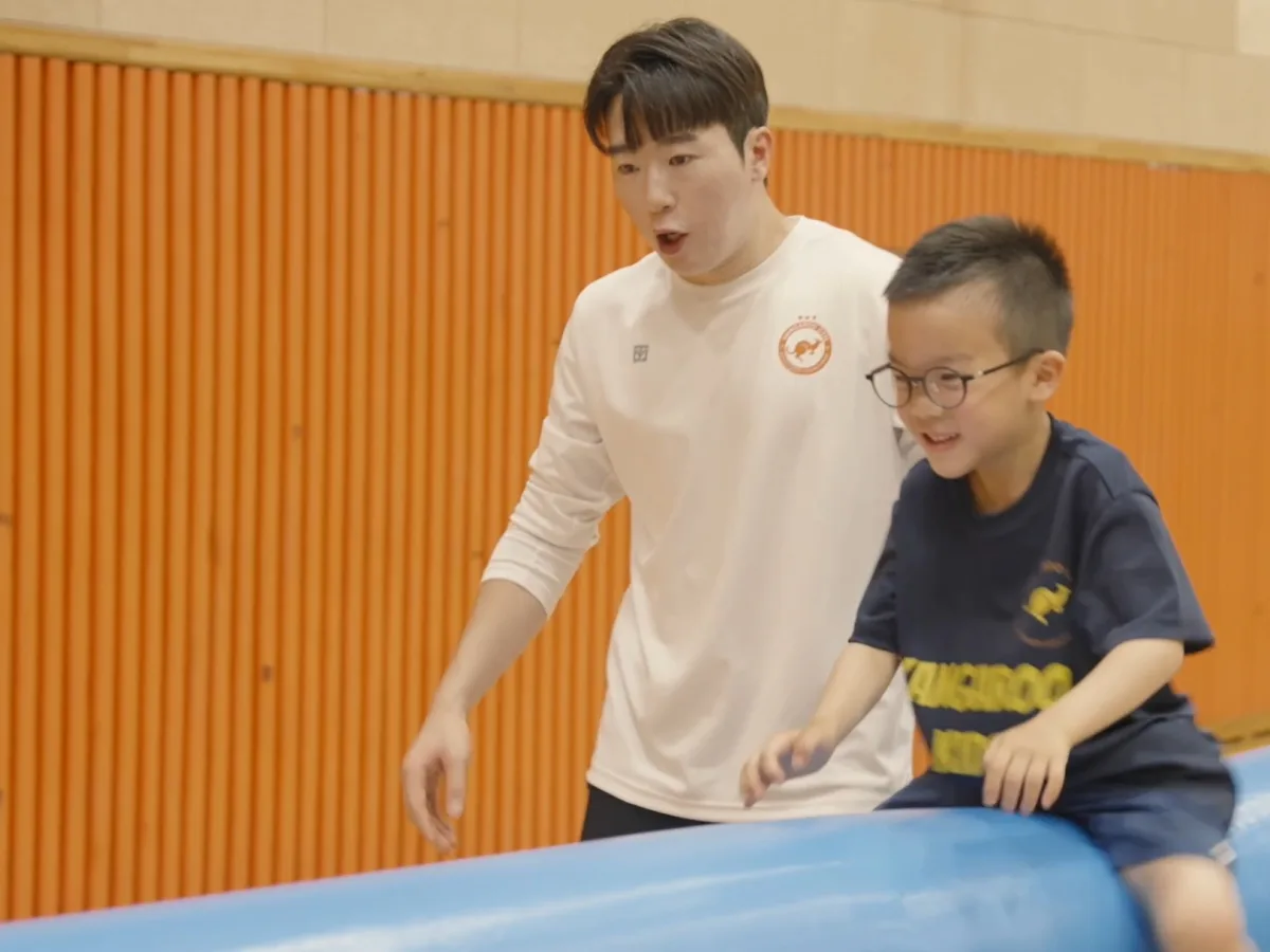선생님이 지켜보는 가운데 원통 장애물을 넘는 아이